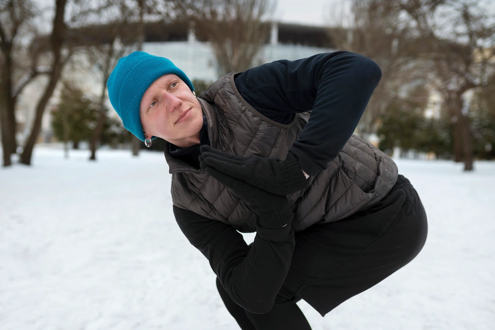 Person holding a painful knee outdoors during cold weather